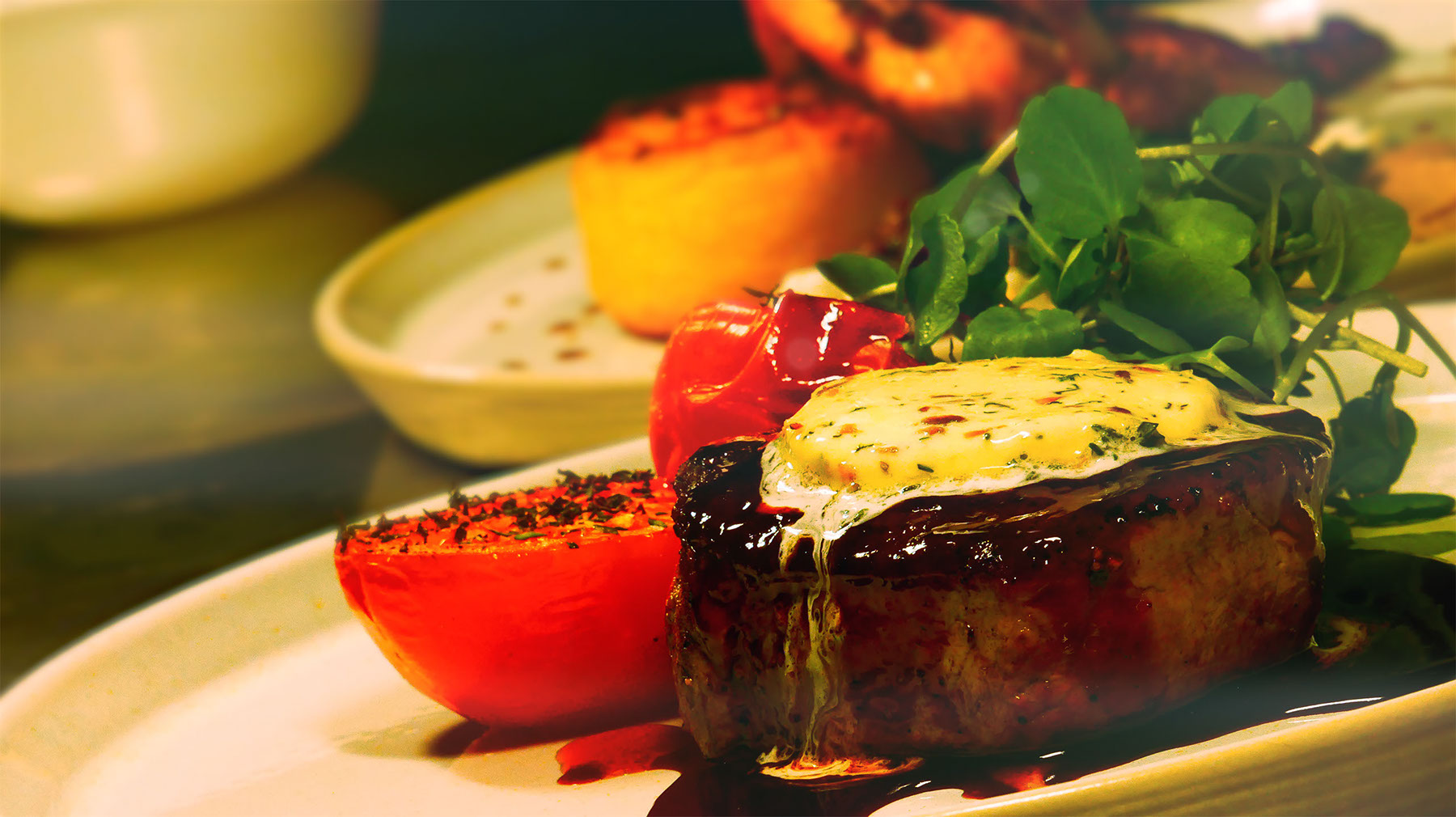 Steak with herb butter, tomato and greens